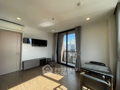 Modern living room with balcony and city view, featuring sleek furniture and natural light.