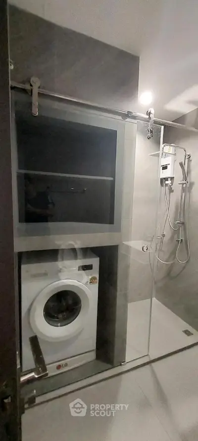 Modern bathroom with integrated washing machine and sleek shower design.