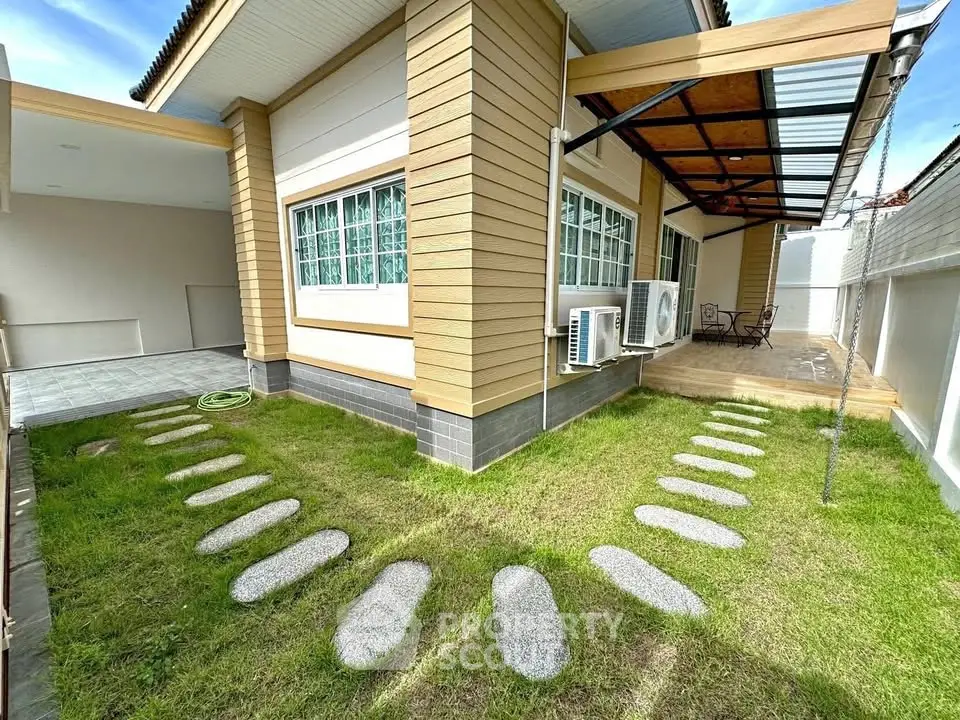 Charming single-story home with modern exterior and lush green lawn, featuring a cozy patio area for outdoor relaxation.
