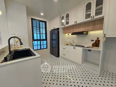 Modern kitchen with sleek black sink and spacious fridge in elegant white cabinetry.