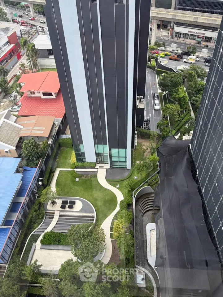 Stunning aerial view of modern high-rise building with lush landscaped garden and cityscape backdrop.