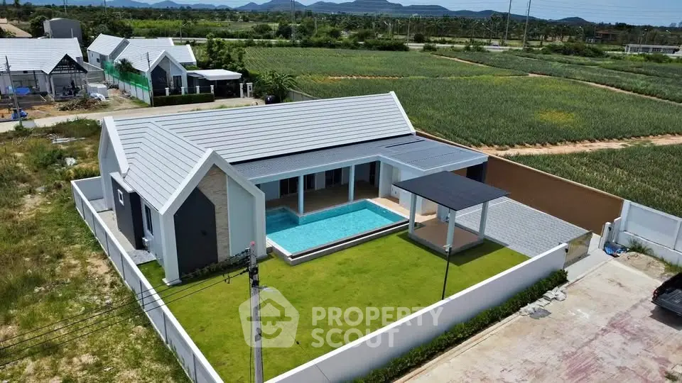 Modern single-story house with private pool and spacious lawn, surrounded by lush greenery and scenic views.