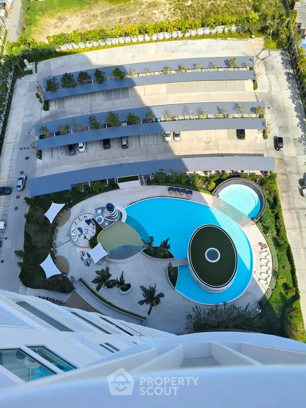Stunning aerial view of luxury apartment complex with pool and parking area.