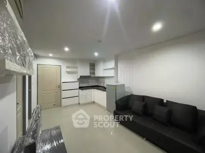 Modern living room with sleek black sofa and compact kitchen in open layout