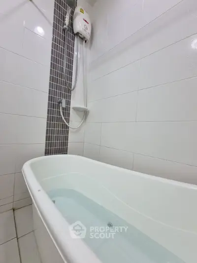 Modern bathroom with bathtub and shower in sleek white tile design.