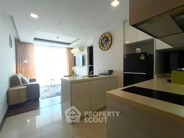 Modern open-layout living room with kitchen, featuring sleek design and ample natural light.