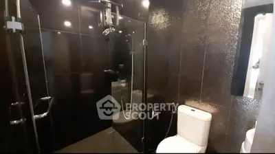 Luxurious modern bathroom with sleek black tiles and glass shower enclosure.