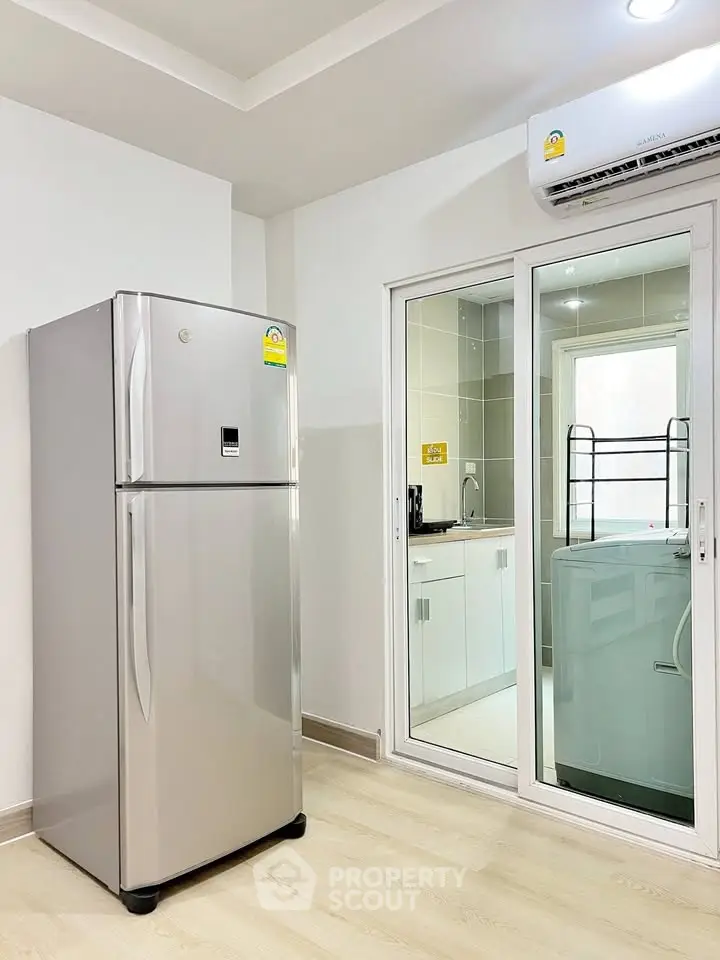 Modern kitchen with stainless steel fridge and washing machine in sleek apartment.