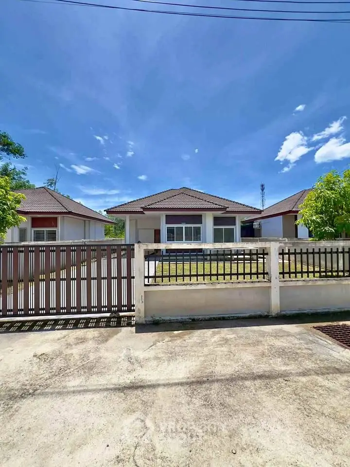 Charming single-story house with spacious front yard and gated entrance under clear blue sky.