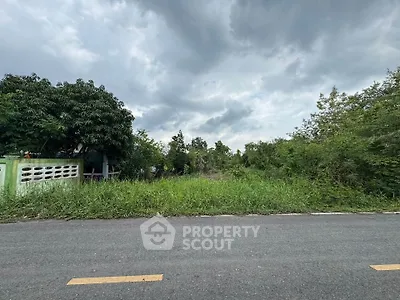 Vacant land plot with lush greenery and clear sky, ideal for development.