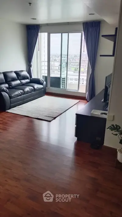 Spacious living room with city view, hardwood floors, and modern furnishings in a high-rise apartment.