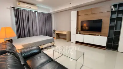 Modern studio apartment with sleek furniture and large TV