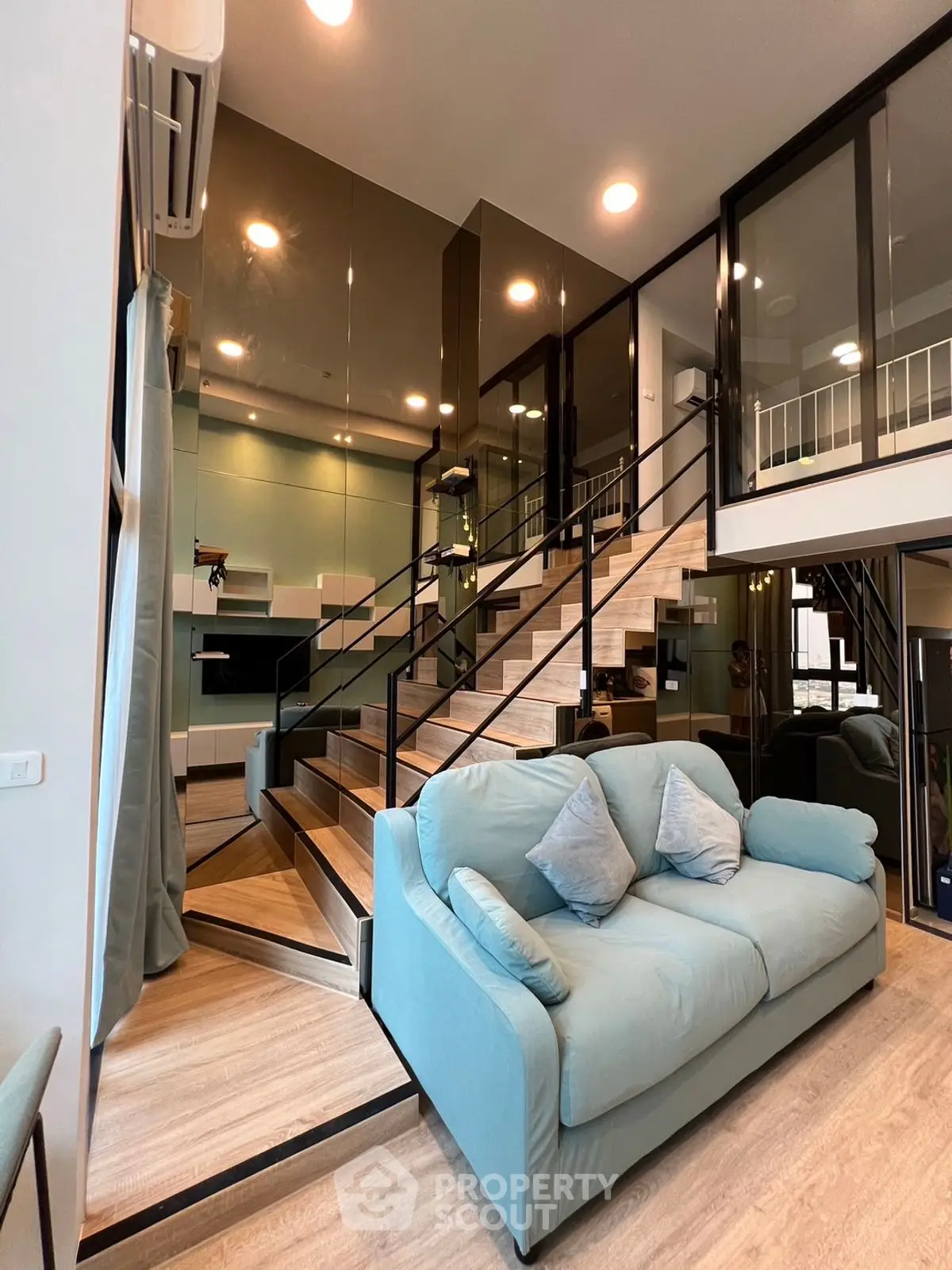 Modern duplex living room with stylish staircase and cozy blue sofa