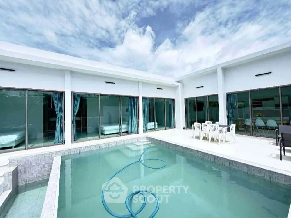 Luxurious modern villa with private pool and spacious patio under a clear blue sky.