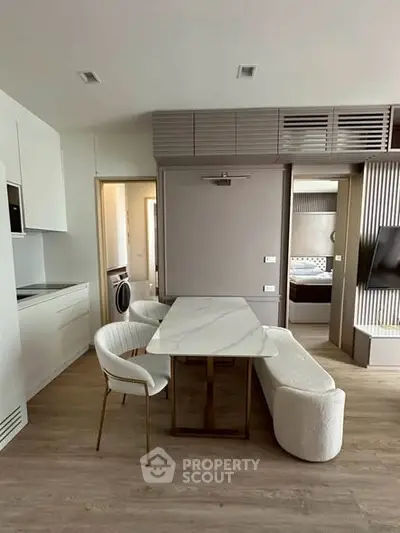 Modern open-plan living area with stylish dining set and sleek kitchen design.