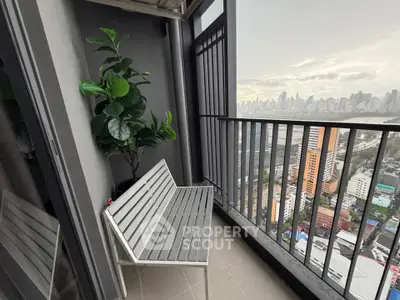 Modern balcony with city skyline view, featuring sleek metal bench and lush potted plant.