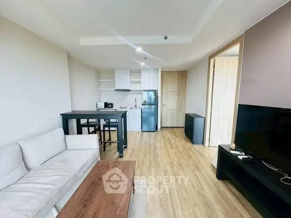 Modern living room with open kitchen, stylish furniture, and wooden flooring in a contemporary apartment.
