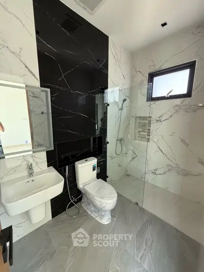 Modern bathroom with marble tiles and glass shower enclosure