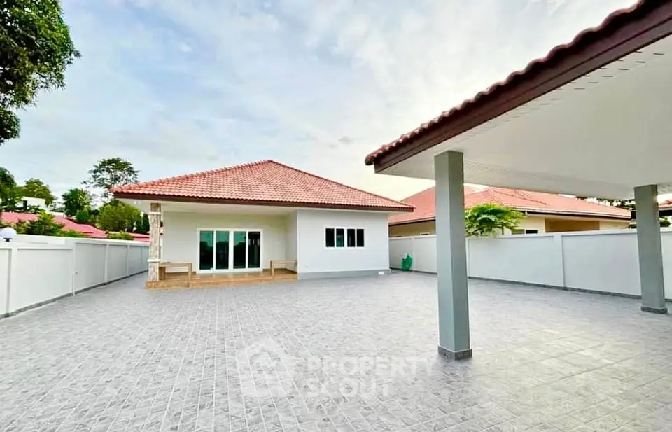 Spacious single-story home with tiled patio and red roof, perfect for family living.
