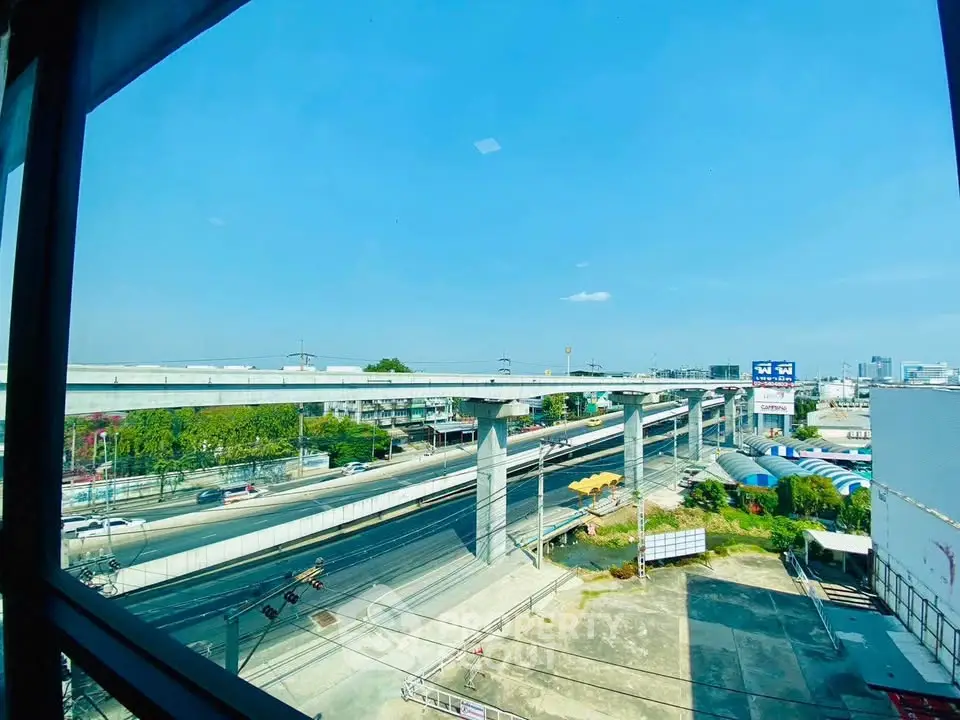 Stunning urban view from high-rise window showcasing elevated highways and cityscape under clear blue sky.