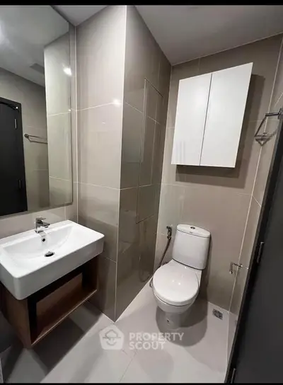 Modern bathroom with sleek fixtures and neutral tiles, featuring a wall-mounted sink and toilet.