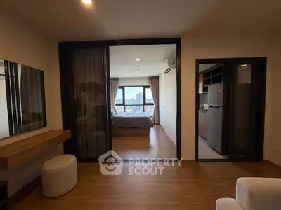 Modern apartment interior with bedroom and kitchen, featuring wood flooring and city view.