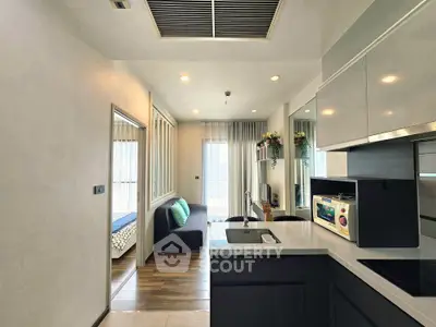 Modern open-layout kitchen with sleek cabinetry and cozy living area, featuring natural light and stylish decor.