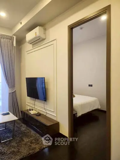 Modern living room with sleek TV setup and view into cozy bedroom, perfect for urban living.