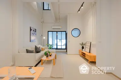 Bright and airy modern living room with high ceilings, sleek furniture, and abundant natural light streaming through large windows, perfect for urban living.