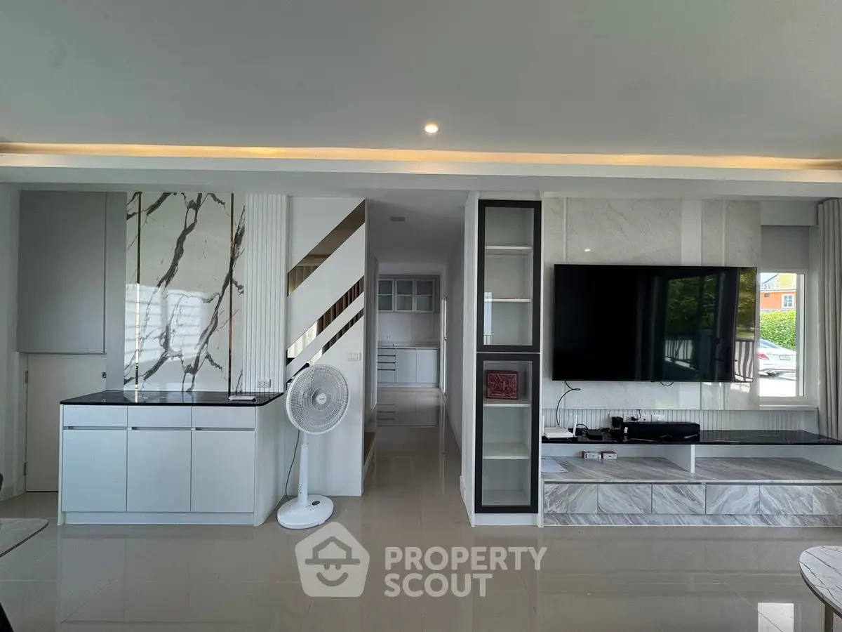 Modern living room with sleek design, large TV, and marble accents for luxurious ambiance.