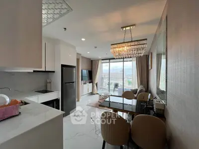 Modern open-layout kitchen and living room with elegant chandelier and balcony view.