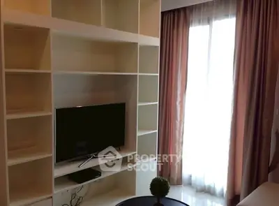 Modern living room with built-in shelves and TV near large window with curtains.