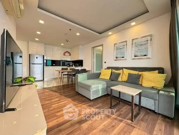 Modern living room with open kitchen, stylish decor, and cozy seating area.