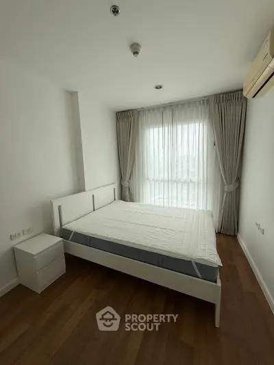 Spacious bedroom with large window and modern furnishings, perfect for comfort and relaxation.