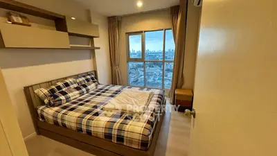 Cozy bedroom with city view, featuring modern decor and large window.