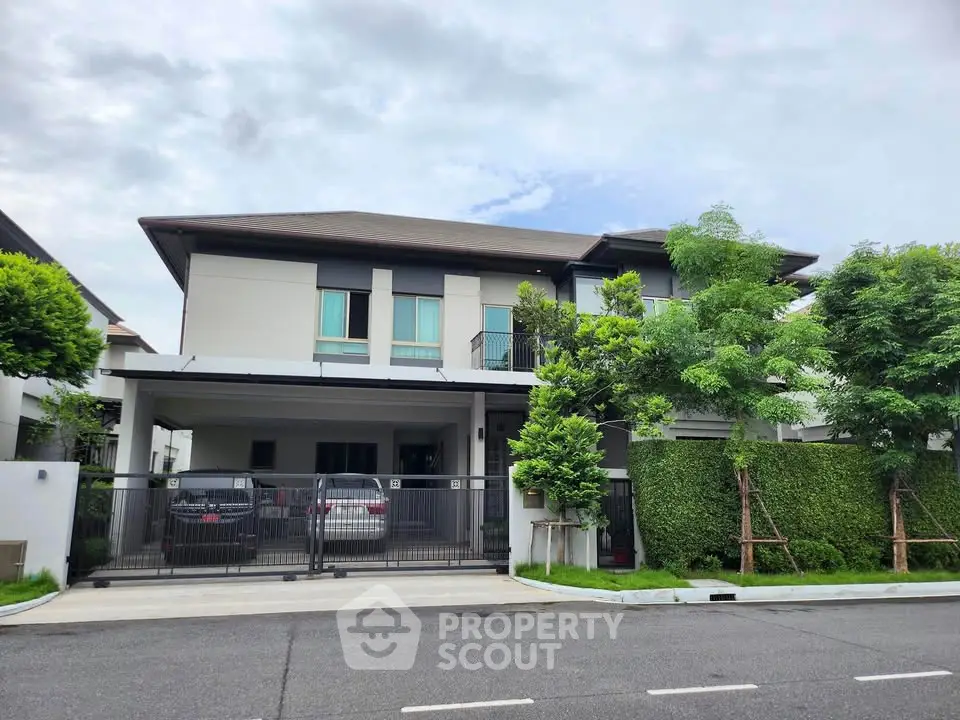 Modern two-story house with garage and lush greenery in a serene neighborhood.