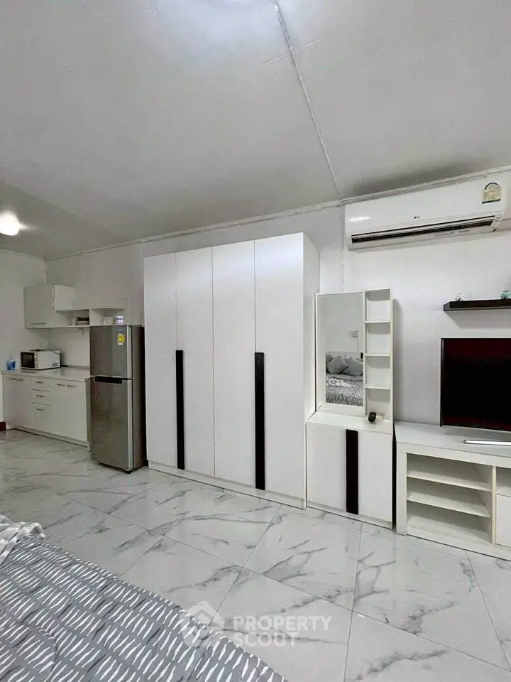 Modern studio apartment with sleek white furniture and marble flooring.