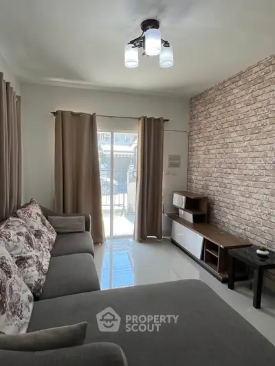 Modern living room with stylish brick accent wall and cozy sectional sofa, featuring natural light from large window.