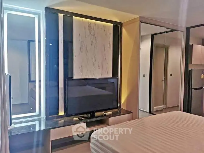 Modern bedroom with stylish decor and built-in TV unit in a contemporary apartment.