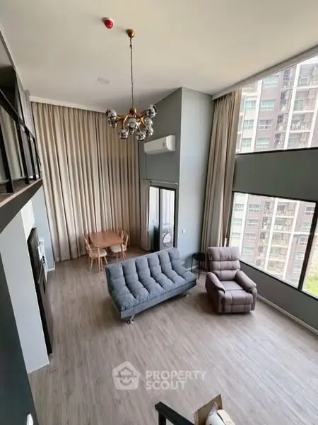 Spacious modern living room with high ceilings and large windows in a stylish apartment.