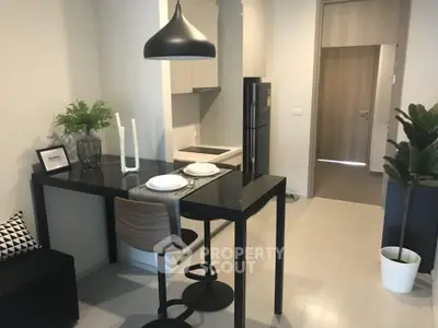 Modern kitchen with sleek black dining table and stylish pendant lighting in a contemporary apartment.