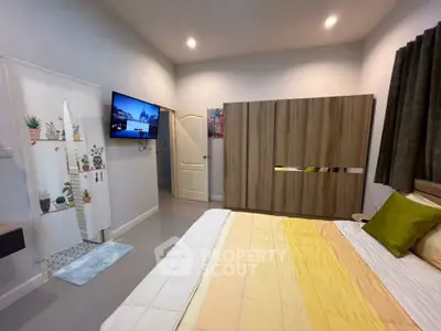Cozy bedroom with modern decor, featuring a wall-mounted TV and stylish wardrobe.