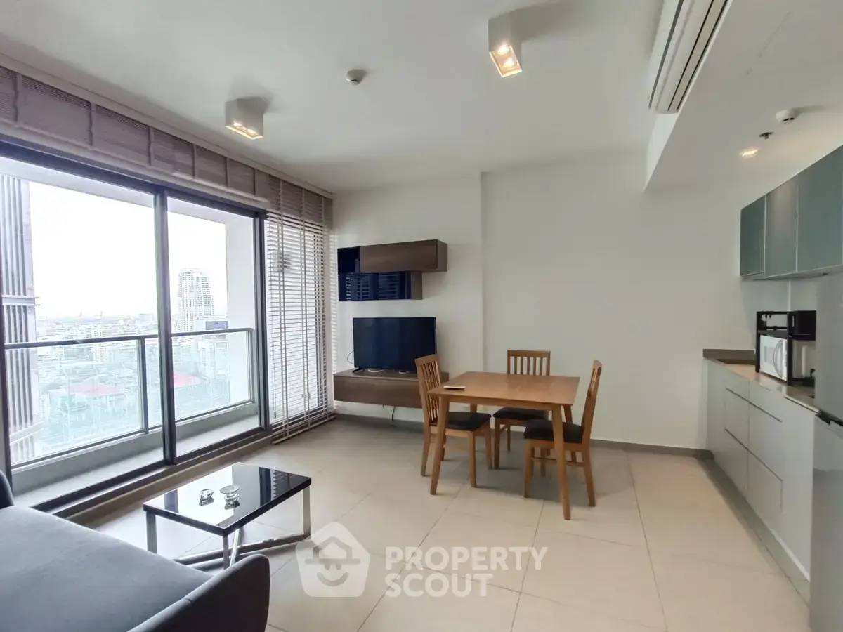 Modern living room with open kitchen and city view balcony in high-rise apartment.