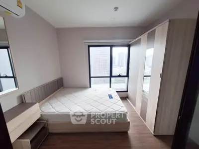 Modern bedroom with large window and wooden furniture in urban apartment