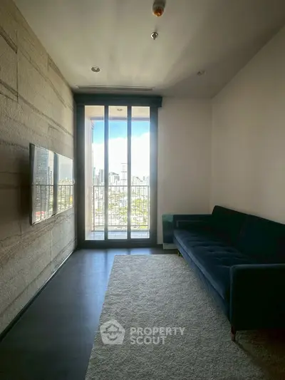 Modern living room with large window offering stunning city view, featuring sleek TV and comfortable sofa.