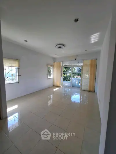 Spacious sunlit living room with large windows and tiled flooring