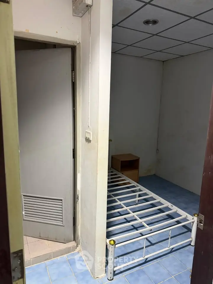 Compact bedroom with metal bed frame and blue tiled floor, ideal for minimalist living.