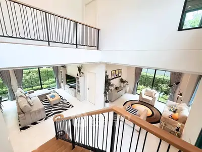 Spacious modern living room with high ceilings and large windows overlooking lush greenery.