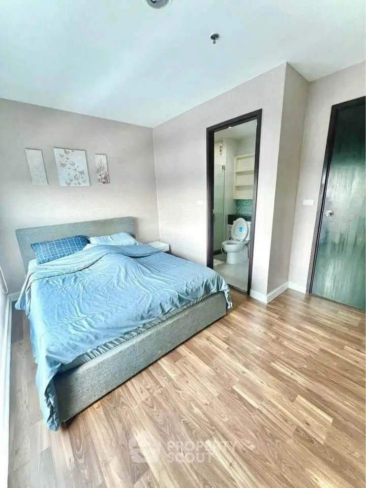Modern bedroom with ensuite bathroom and wooden flooring in a stylish apartment.
