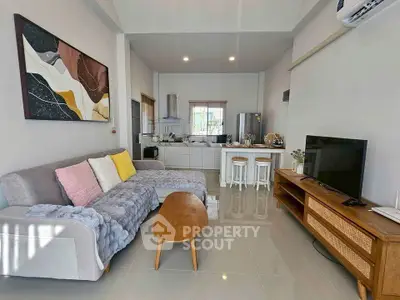 Modern living room with open kitchen, stylish decor, and cozy seating area.